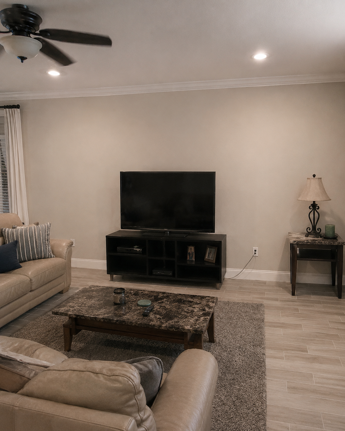 Before photo of an Apopka living room wall with a plain painted wall, a freestanding TV stand, and a television before the custom built-in installation.