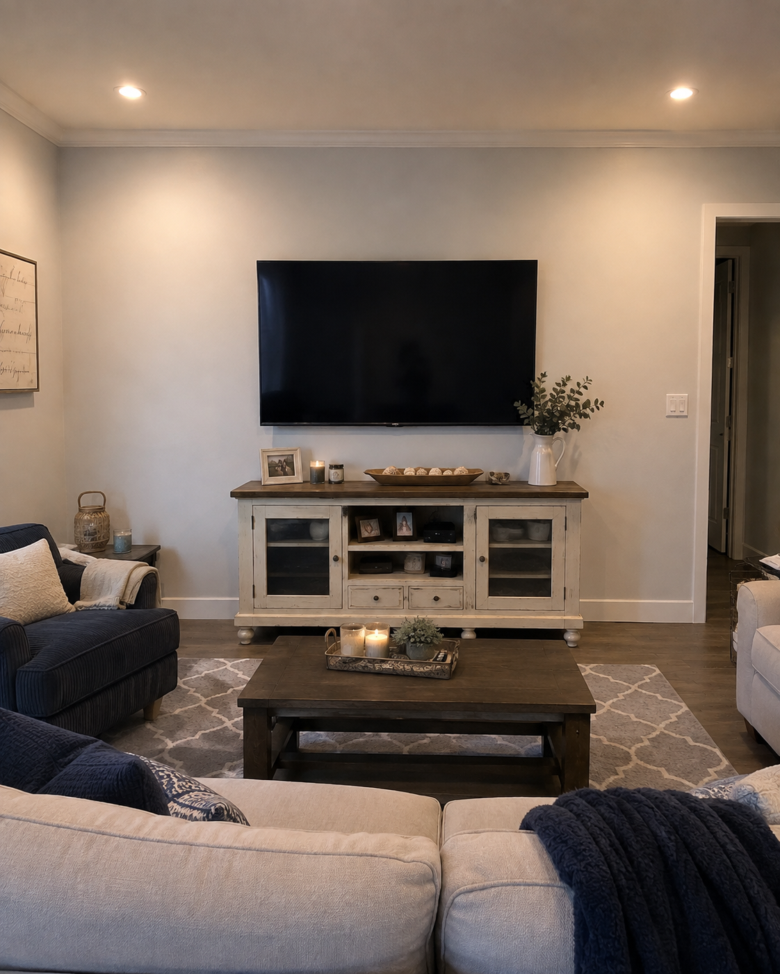 Before view of the Altamonte Springs living room with a plain wall, wall-mounted TV, and freestanding console before the Custom Fireplace TV Wall installation.