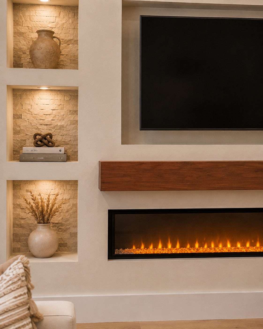 Detail view of the Longwood Custom Fireplace TV Wall showing natural stone niche backing, warm niche lighting, stained wood mantel, recessed TV area, and electric fireplace.