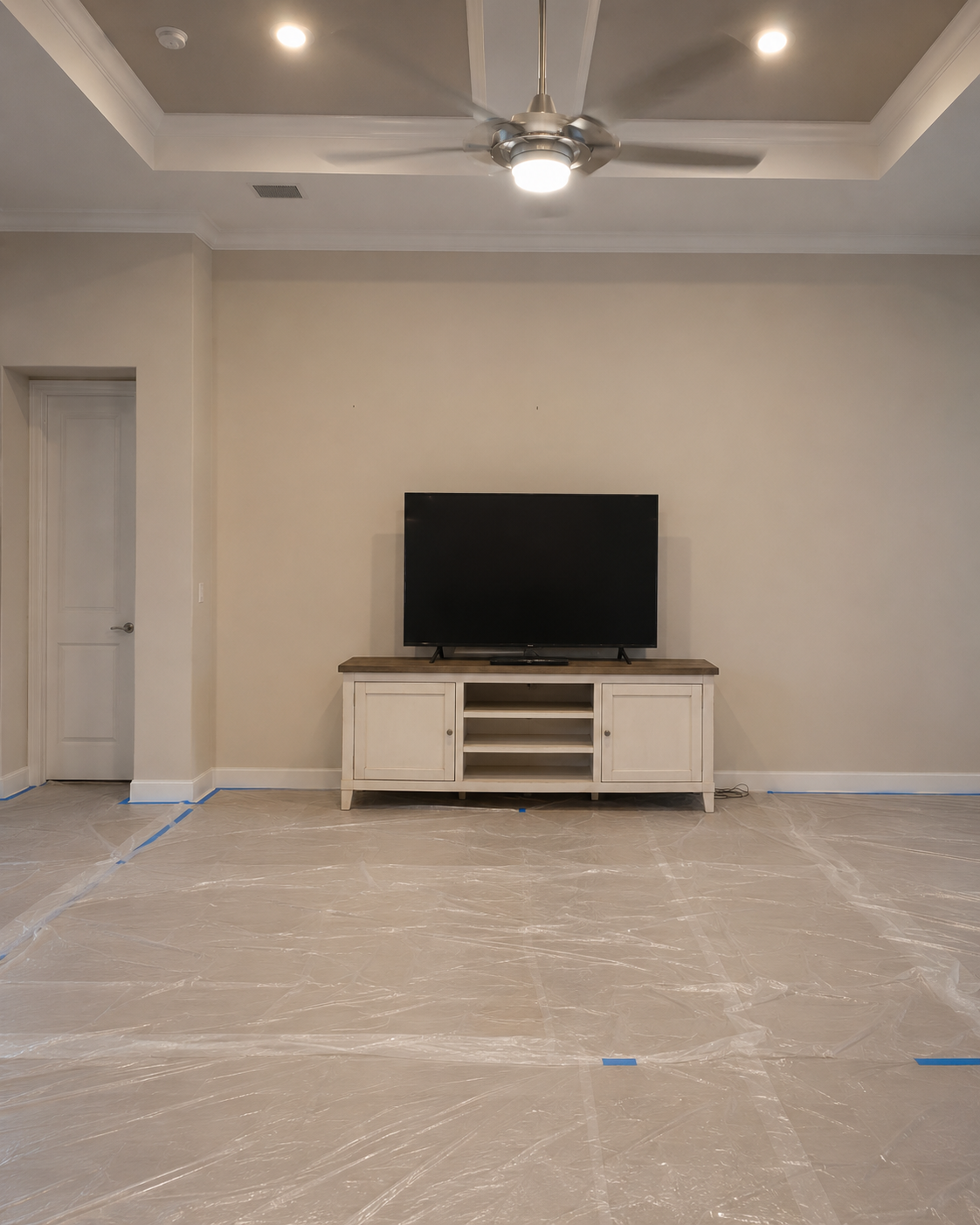 Before view of the Maitland living room with a blank wall, freestanding TV console, and television before the Custom Fireplace TV Wall was built.